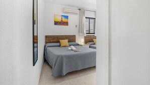 A bedroom with a bed, a nightstand, a lamp, a painting, and an air conditioning unit. - Room '104' with Wi-Fi and Air Conditioning (Conil de la Frontera)