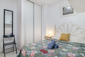 Une chambre à coucher avec un lit, une table de chevet, une lampe, un miroir et une armoire.