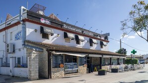 Un restaurant appelé « Restaurante Avenida », doté d’une façade en pierre, de places assises en plein air et d’un menu affiché en évidence.