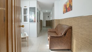 A hallway with a brown leather sofa, a white cabinet, and a small table with a sign. - Room '109' with Wi-Fi and Air Conditioning (Conil de la Frontera)