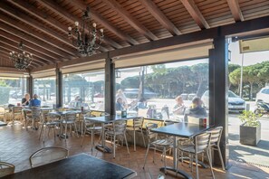 An outdoor cafe with tables and chairs, large windows, and a wooden ceiling. - Double Room - 4 with Wi-Fi and Air Conditioning (Conil de la Frontera)