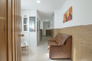 A hallway with a brown leather sofa, a white cabinet, and a small table with a sign. - Room '112' with Wi-Fi and Air Conditioning (Conil de la Frontera)