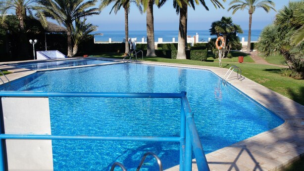 A swimming pool with a blue border, a lifebuoy, and a view of the sea. - Apartment 'Gaby' with Sea Views, Wi-Fi and Air Conditioning (Denia)