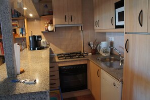 A compact kitchen with a gas stove, microwave, sink, and dishwasher.