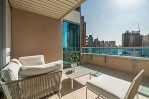 A balcony with a sofa, a small table, and a potted plant. - Silkhaus Al Mass (Dubai)