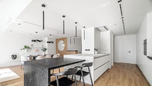A modern kitchen with a marble countertop, black chairs, and pendant lighting. - Silkhaus Al Mass (Dubai)