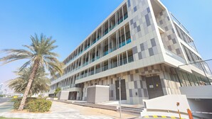 A modern multi-story building with a geometric facade, large windows, and a palm tree in the foreground. - Silkhaus Al Raha Lofts 2 (Abu Dhabi)