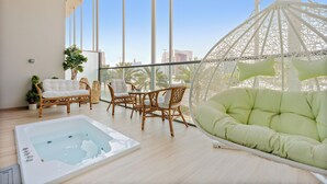A spacious balcony with wicker furniture, a green cushioned sofa, and a hot tub. - Silkhaus Al Raha Lofts 2 (Abu Dhabi)