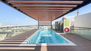 Una piscina en la azotea con vistas a la ciudad, un flotador salvavidas y una pérgola.