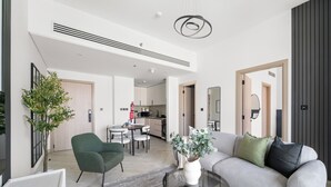 Una sala moderna con un sofá gris, un sillón verde, una mesa de centro redonda y una planta en maceta.