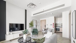 Una sala de estar moderna con una televisión de pantalla plana, un sofá, una mesa de centro y una zona de comedor con una mesa y sillas.