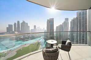 A balcony with a glass railing overlooking a cityscape and a river.