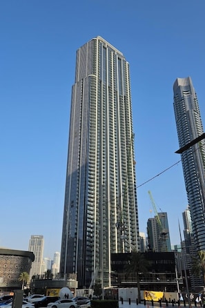 A tall, modern skyscraper with a grid-like facade, surrounded by other high-rise buildings and a construction site in the background.