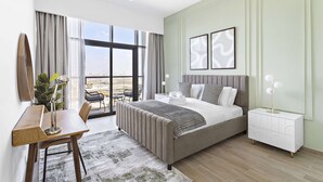 Ein modernes Schlafzimmer mit einem großen Bett, Nachttischen, einem Schreibtisch und Blick auf die Stadt.