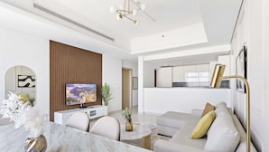 Ein modernes Wohnzimmer mit einem Esstisch aus Marmor, einer Couch und einem Fernseher.