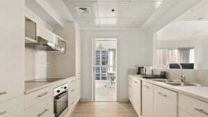 A modern kitchen with white cabinets, stainless steel appliances, and a view to a balcony. - Silkhaus Marina Quays West (Dubai)