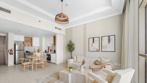 A spacious living area with a dining table, sofa, and coffee table, connected to a kitchen with modern appliances. - Silkhaus Reflection Tower (Abu Dhabi)