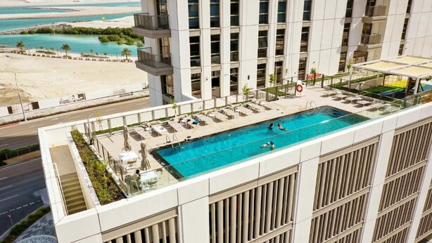A rooftop pool with a view of the beach and ocean. - Silkhaus Reflection Tower (Abu Dhabi)