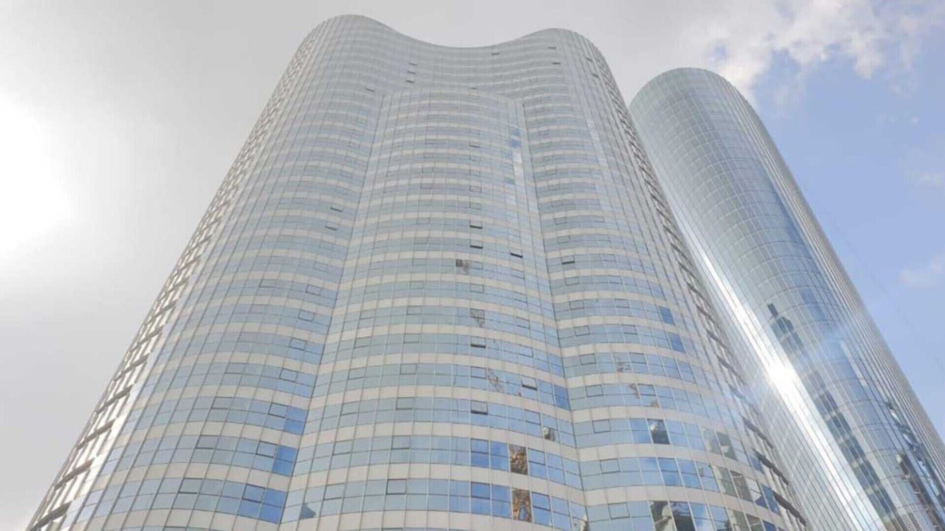 Un grand immeuble moderne en verre, doté d’une façade incurvée.