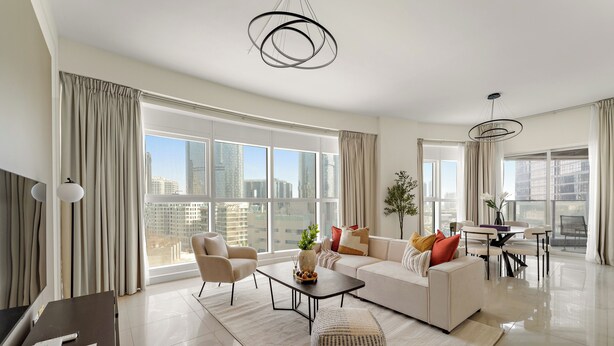 Una sala moderna con un sofá, sillones, una mesa de comedor y un televisor.