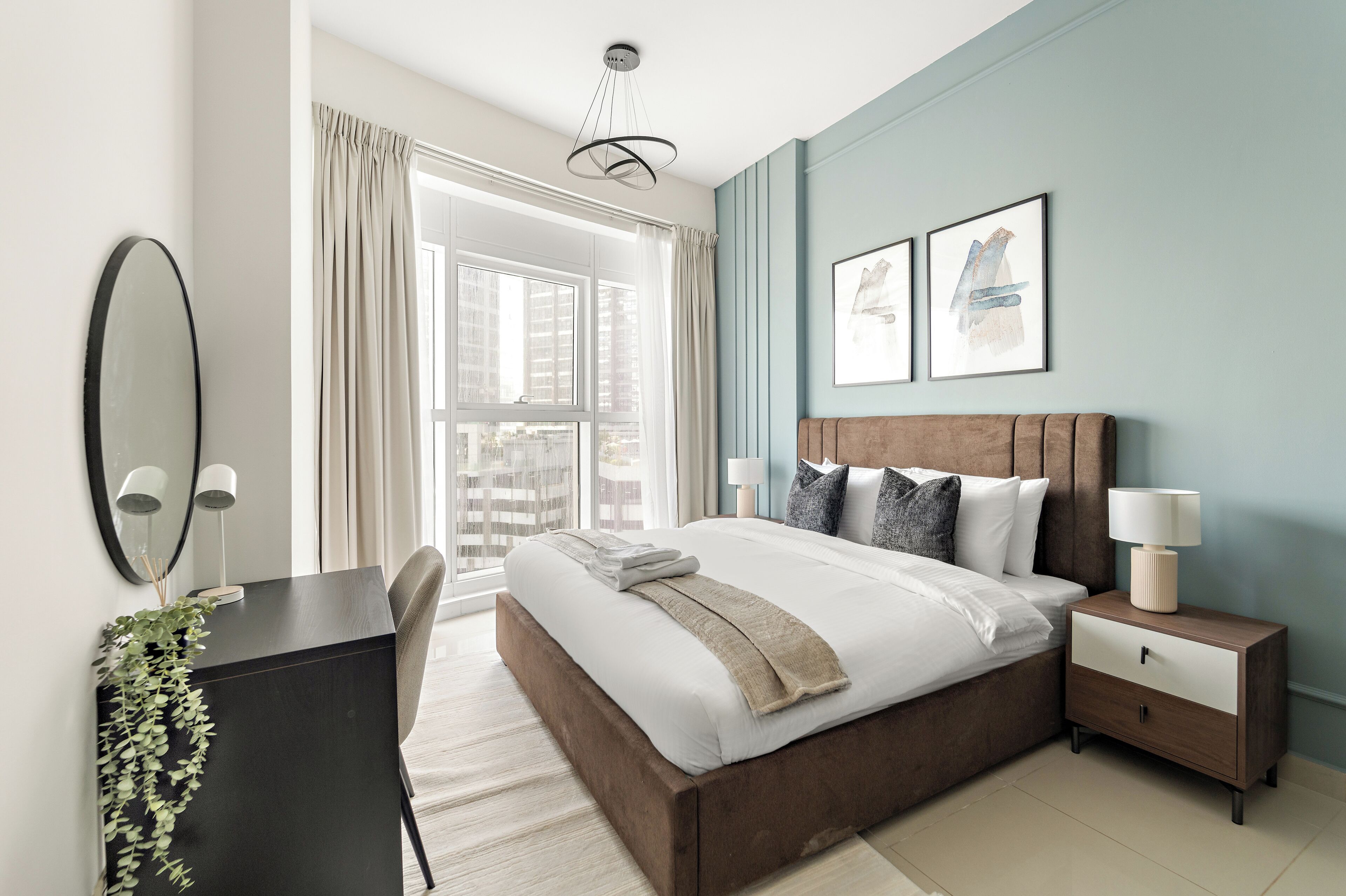 Une chambre moderne avec un grand lit, des tables de chevet, un bureau et une fenêtre avec des rideaux.