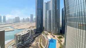 Un edificio de gran altura con fachada curva, una estructura de estacionamiento y una masa de agua al fondo.