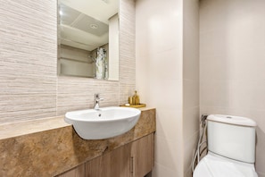 A bathroom with a marble sink, a mirror, and a toilet.
