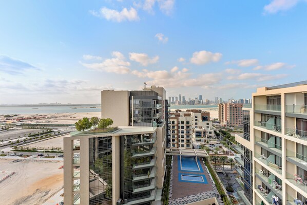 A high-rise building with multiple balconies overlooking a beach and a city skyline.