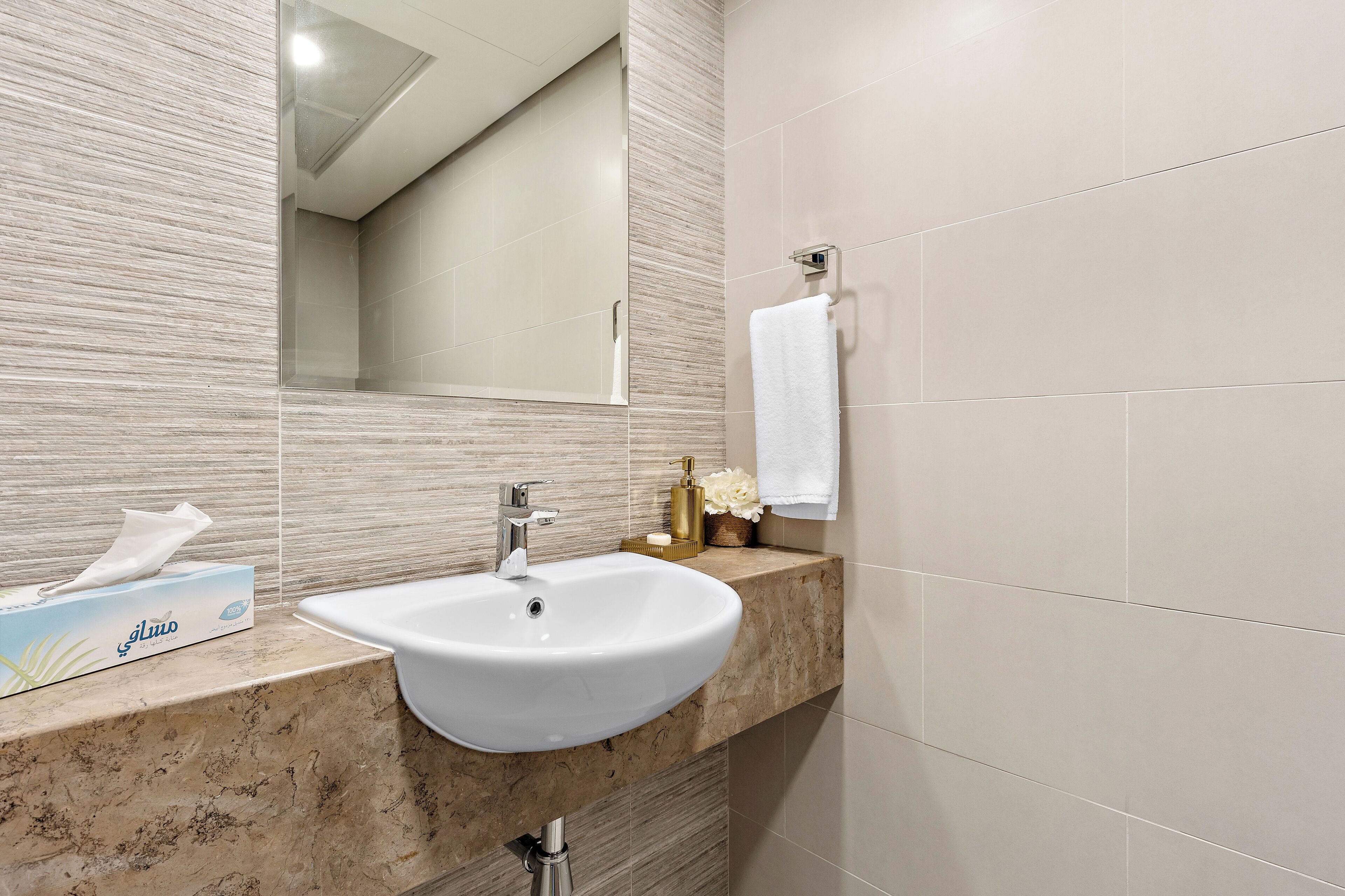 Une salle de bain équipée d’un lavabo, d’un miroir et d’un porte-serviettes.