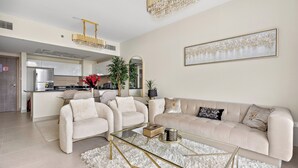 A modern living room with a beige sofa, a glass coffee table, and a chandelier. - Silkhaus Soho Square (Abu Dhabi)