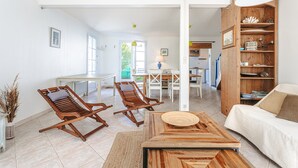 Amplia sala de estar con sofá, dos sillones de madera, una mesita de centro y una estantería de madera.