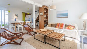 Una sala de estar con sofá, sillas de madera, una mesa de centro, una escalera y un comedor.