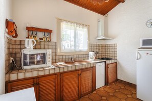 A compact kitchen with a microwave, coffee maker, and a stove. - Charming Detached House with Terrace, Garden, and Garage 5 Minutes from the Beaches (Saint-Trojan-les-Bains)