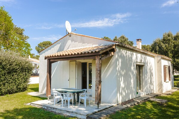 Uma casa pequena com varanda, antena parabólica e chaminé.