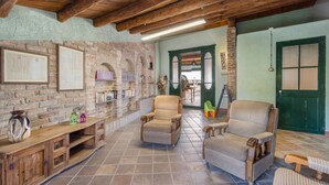 A rustic interior with exposed brick walls, wooden beams, wicker furniture, and a tiled floor.