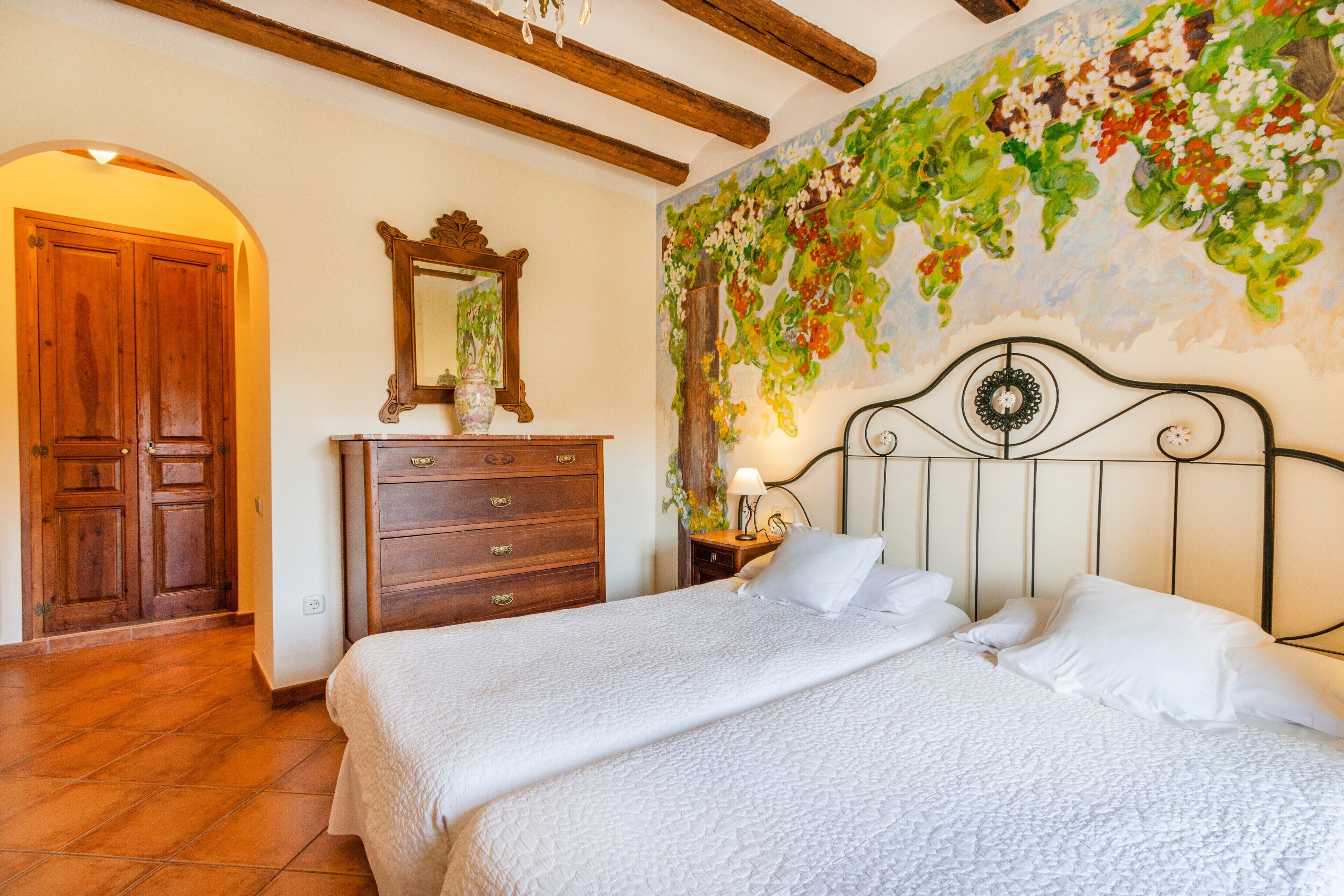 Una camera da letto con un letto, un armadio in legno e un muro decorato con un murale floreale.