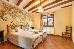 Un dormitorio con dos camas, techo de madera, radiador, ventana con cortinas y una silla.