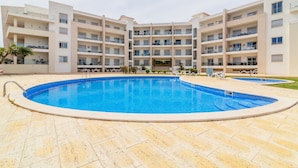 A multi-story building with a central swimming pool surrounded by a tiled deck.
