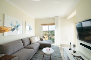A modern living room with a sofa, a small coffee table, a flat-screen TV, and artwork on the walls.