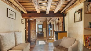 Una habitación acogedora con vigas de madera, un sofá, un sillón y una estantería.