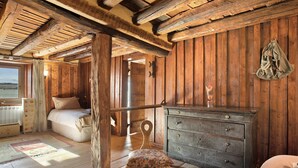 Una habitación rústica de madera con una cama, cómoda y vistas al exterior.