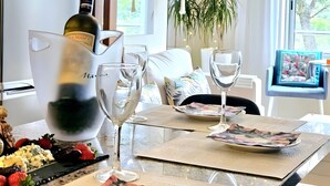 Een eettafel met een fles wijn, glazen en een bord eten.