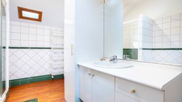 A bathroom with a white sink, mirror, and tiled walls.