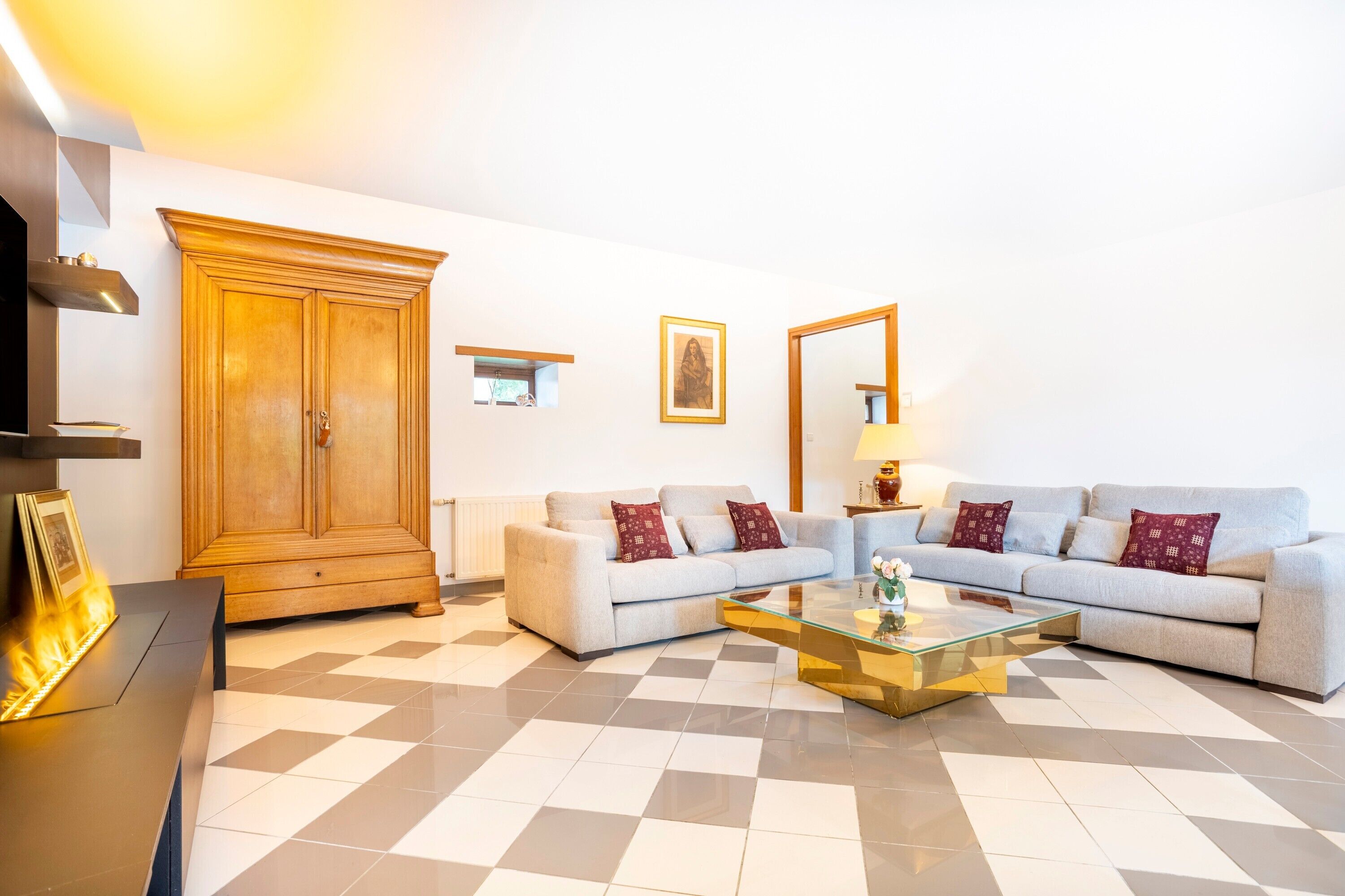A living room with a sofa, a glass coffee table, a wooden cabinet, a fireplace, and a wall-mounted TV.