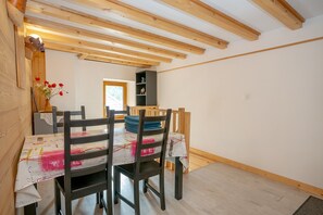Ein Essbereich mit Holzbalken, einem Tisch mit weißem Tuch und Stühlen.