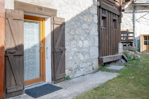 Un edificio rústico de piedra con puerta de madera y ventanas con contraventanas.