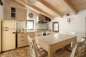 Una cocina con techo de madera, una mesa de comedor con sillas y un refrigerador.