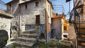 A stone building with a staircase leading to a door, surrounded by other buildings. - Apartment 'Merlino' with Balcony, Wi-Fi and Air Conditioning (Biassa)
