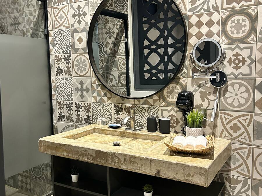 Un baño con lavamanos doble, un espejo grande, una planta pequeña en maceta y una repisa con plantas en macetas.