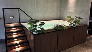 A modern bathroom with a wooden vanity, a built-in bathtub, and a staircase. - Wizard (Playas de Rosarito)
